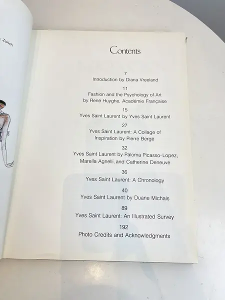 Foto de um(a) Livro capa dura Yves Saint Laurent 1983, da categoria de Livros. Maravilhoso livro capa dura em tecido, em inglês, de 1983. Marcas do tempo e uso. Mostrado de uma perspectiva diferente. Vendido no marketplace Trésors.