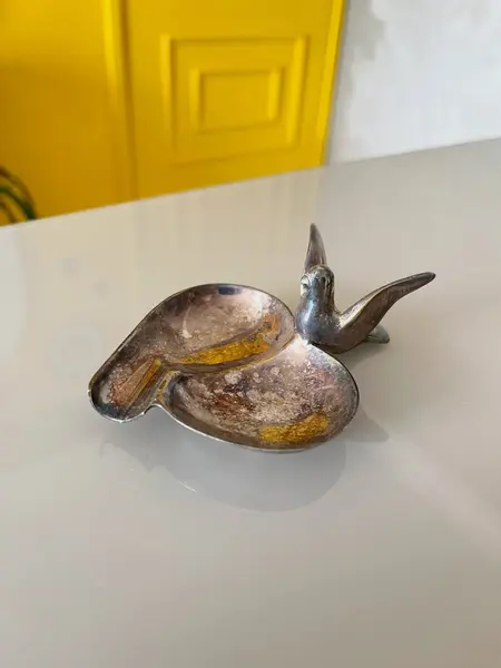 Foto de um(a) ​Cinzeiro pássaro em metal, da categoria de Cinzeiros. Cinzeiro em metal possivelmente banhado a prata. Apresenta oxidações no banho e leves marcas do tempo e uso como nas fotos. ... Mostrado de uma perspectiva diferente. Vendido no marketplace Trésors.