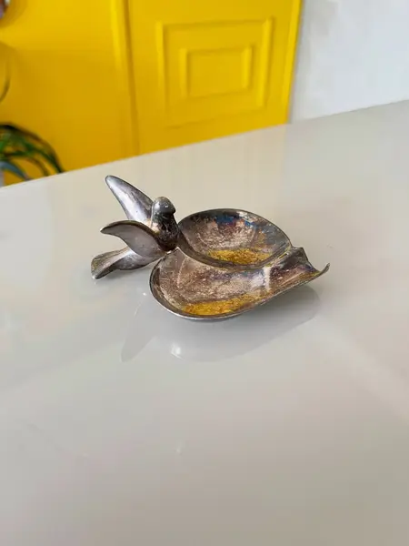 Foto de um(a) ​Cinzeiro pássaro em metal, da categoria de Cinzeiros. Cinzeiro em metal possivelmente banhado a prata. Apresenta oxidações no banho e leves marcas do tempo e uso como nas fotos. ... Mostrado de uma perspectiva diferente. Vendido no marketplace Trésors.