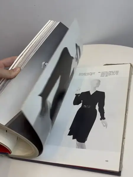 Foto de um(a) Livro capa dura Yves Saint Laurent 1983, da categoria de Livros. Maravilhoso livro capa dura em tecido, em inglês, de 1983. Marcas do tempo e uso. Mostrado de uma perspectiva diferente. Vendido no marketplace Trésors.