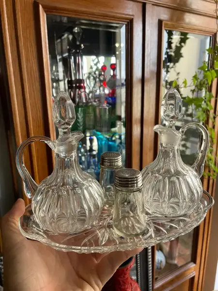 Foto de um(a) Antigo Galheteiro Saleiro Em Cristal Francês, da categoria de Saleiros e pimenteiros. Antigo galheteiro em cristal francês prensado. Composto por cinco peças. **Uma das garrafinhas tem um lascado na borda.... Mostrado de uma perspectiva diferente. Vendido no marketplace Trésors.