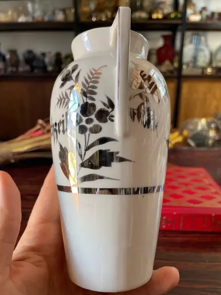 Foto de um(a) Antigo Vasinho Art Deco Em Porcelana Alemã Pintado Prata, da categoria de Vasos. Antigo e lindo vasinho em porcelana alemã. Pintado à mão com prata de lei Período Art DecoMedidas 16x10cmBocal 6cm. Mostrado de uma perspectiva diferente. Vendido no marketplace Trésors.