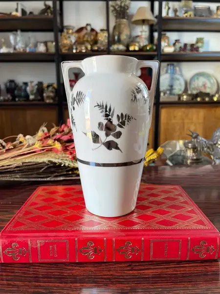 Foto de um(a) Antigo Vasinho Art Deco Em Porcelana Alemã Pintado Prata, da categoria de Vasos. Antigo e lindo vasinho em porcelana alemã. Pintado à mão com prata de lei Período Art DecoMedidas 16x10cmBocal 6cm. Mostrado de uma perspectiva diferente. Vendido no marketplace Trésors.