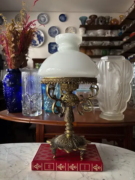 Foto de um(a) Antiga Luminária Clássica Abajur De Mesa Bronze E Opalina, da categoria de Abajures. Antigo e lindo abajur com estrutura em bronze todo trabalhado e cúpula em opalina branca. Todo original. Medidas 36x19cm. Mostrado de uma perspectiva diferente. Vendido no marketplace Trésors.