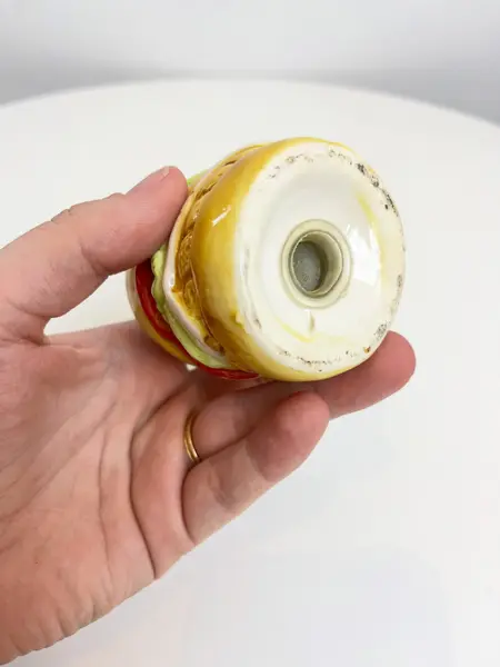Foto de um(a) Saleiro em cerâmica formato hamburguer, da categoria de Saleiros e pimenteiros. Saleiro em cerâmica com tampa na base em silicone. Perfeito estado. Medidas: 7x5cm. Mostrado de uma perspectiva diferente. Vendido no marketplace Trésors.