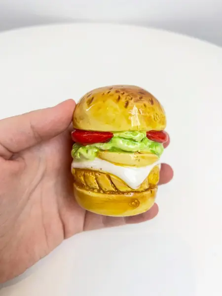 Foto de um(a) Saleiro em cerâmica formato hamburguer, da categoria de Saleiros e pimenteiros. Saleiro em cerâmica com tampa na base em silicone. Perfeito estado. Medidas: 7x5cm. Mostrado de uma perspectiva diferente. Vendido no marketplace Trésors.