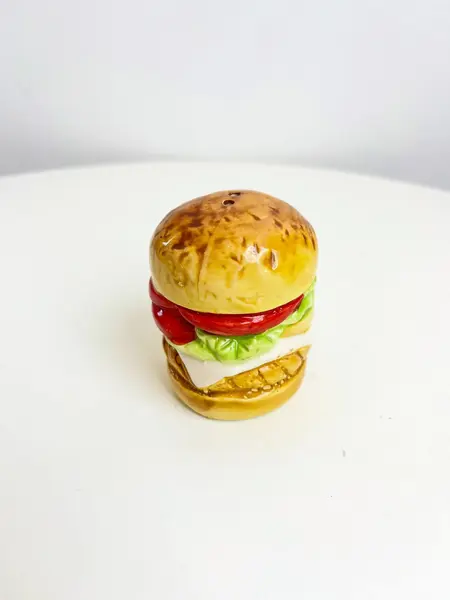 Foto de um(a) Saleiro em cerâmica formato hamburguer, da categoria de Saleiros e pimenteiros. Saleiro em cerâmica com tampa na base em silicone. Perfeito estado. Medidas: 7x5cm. Mostrado de uma perspectiva diferente. Vendido no marketplace Trésors.