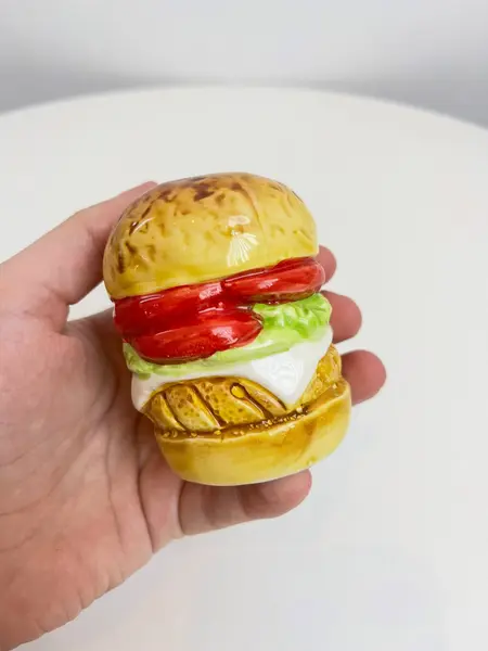 Foto de um(a) Saleiro em cerâmica formato hamburguer, da categoria de Saleiros e pimenteiros. Saleiro em cerâmica com tampa na base em silicone. Perfeito estado. Medidas: 7x5cm. Mostrado de uma perspectiva diferente. Vendido no marketplace Trésors.