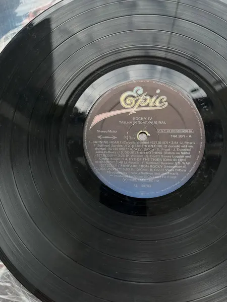 Foto de um(a) ​LP Trilha sonora original de Rocky IV -1982, da categoria de LPs ou Discos de Vinil . LP com a trilha sonora original de Rocky IV, de 1982. Dois mínimos riscos superficiais. Mostrado de uma perspectiva diferente. Vendido no marketplace Trésors.