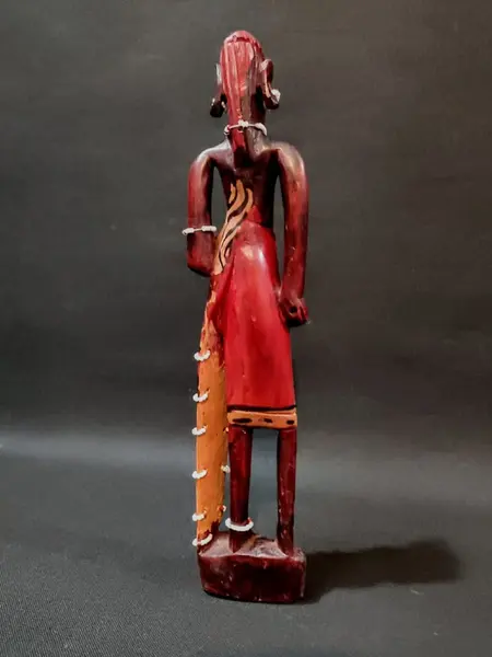 Foto de um(a) Escultura Africana Anos 80, da categoria de Escultura. Escultua africana em madeira policromada com missangas e sementes, década de 1980. A: 30 cm / L: 6,5 cm / P: 4 cm Peso: 248 g. Mostrado de uma perspectiva diferente. Vendido no marketplace Trésors.