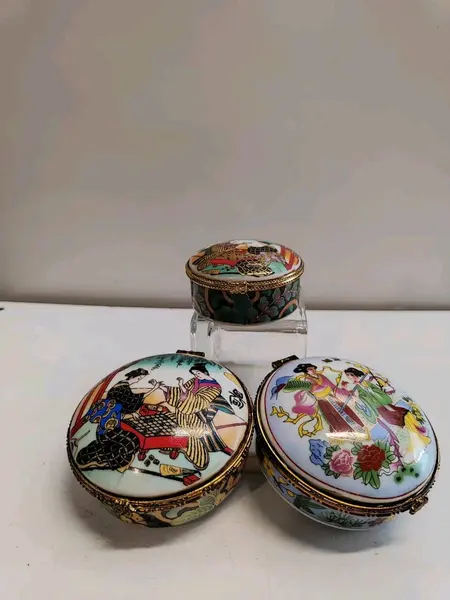 Foto de um(a) Combo com Três Caixas em Porcelana Estampa Cenas Japonesas, Década de 1980, da categoria de Cestos e Caixas. Combo com três caixas em porcelana. Estampas com cenas japonesas, gueixas e flores. Fecho dourado e contorno da caixa com... Mostrado de uma perspectiva diferente. Vendido no marketplace Trésors.