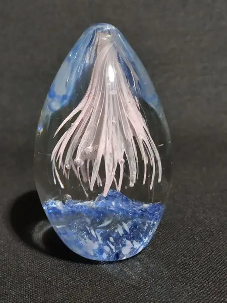 Foto de um(a) Peso de Papel Vidro Anos 80, da categoria de Pesos de papel. Peso de papel em vidro na forma de ovo, transparente, azul e rosinha, década de 1980. A: 8,5 cm / D: 5cm peso: 326g. Mostrado de uma perspectiva diferente. Vendido no marketplace Trésors.