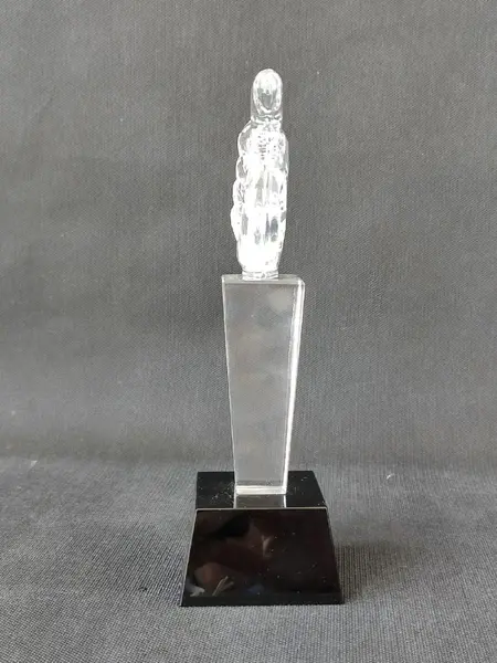 Foto de um(a) Troféu Joinha Cristal, da categoria de Escultura. Escultura em cristal do joinha, base um prisma de quatro faces em cristal preto.A: 21cm Base: 6.5 x 7 x 4.5 cm Peso: 718g. Mostrado de uma perspectiva diferente. Vendido no marketplace Trésors.
