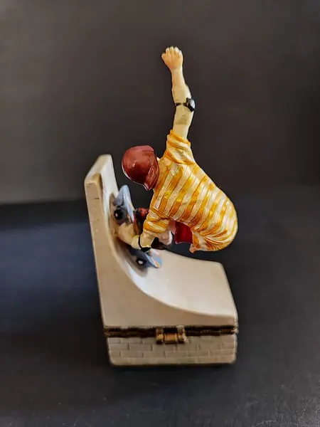 Foto de um(a) Caixinha em Resina Skatista, Década de 2000, da categoria de Cestos e Caixas. Caixa de resina policromada com fecho em latão oxidado, década de 2000.A: 10,6 cm L: 5 cm P: 3,5 cm peso: 99 g. Mostrado de uma perspectiva diferente. Vendido no marketplace Trésors.