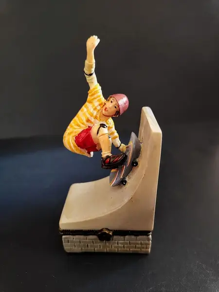 Foto de um(a) Caixinha em Resina Skatista, Década de 2000, da categoria de Cestos e Caixas. Caixa de resina policromada com fecho em latão oxidado, década de 2000.A: 10,6 cm L: 5 cm P: 3,5 cm peso: 99 g. Mostrado de uma perspectiva diferente. Vendido no marketplace Trésors.