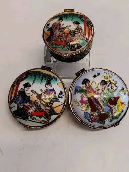 Foto de um(a) Combo com Três Caixas em Porcelana Estampa Cenas Japonesas, Década de 1980, da categoria de Cestos e Caixas. Combo com três caixas em porcelana. Estampas com cenas japonesas, gueixas e flores. Fecho dourado e contorno da caixa com... Mostrado de uma perspectiva diferente. Vendido no marketplace Trésors.