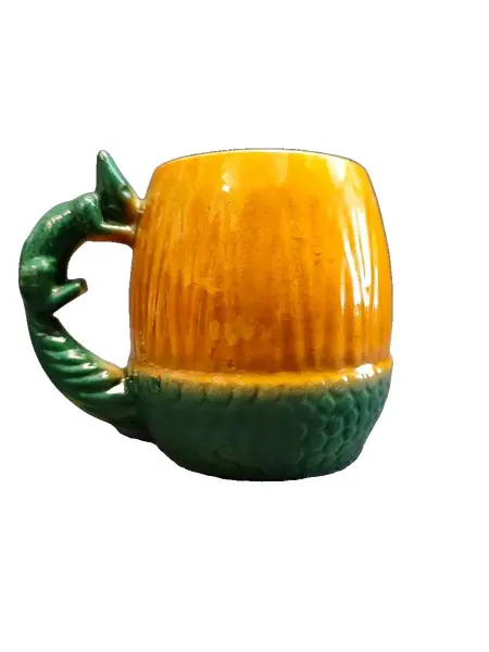 Foto de um(a) Caneco Porcelana em Formato de Nozes e Esquilo, Cerâmica Guarani, Década de 1940, da categoria de Canecas. Caneco porcelana laranja e verde com a forma de noz e esquilo como alça, década de 194. Fabricante: cerâmica guarani A: 11... Vendido no marketplace Trésors.