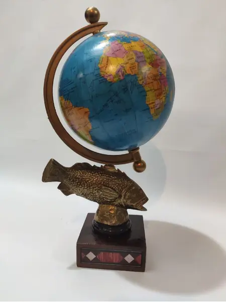 Foto de um(a) Globo Terrestre Latão e Marchetaria anos 70, da categoria de Globos. Globo terrestre de mesa com globo giratório e envelhecido com base de peixe em latão e madeira com marchetaria adesivada... Mostrado de uma perspectiva diferente. Vendido no marketplace Trésors.