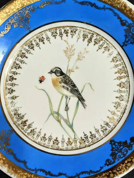 Foto de um(a) Prato Porcelana Dom Pedro, Rio de Janeiro, Década de 1940, da categoria de Pratos Decorativos. Prato de parede policromado e filetado e arabescos em toda a borda. Parte interna com pintura de um passarinho sobre ramos.... Mostrado de uma perspectiva diferente. Vendido no marketplace Trésors.