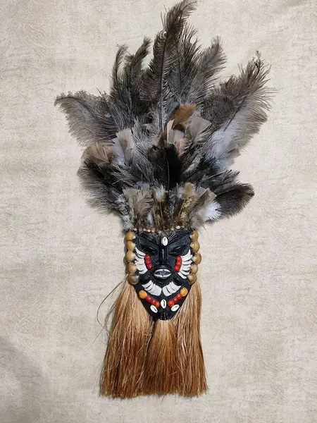 Foto de um(a) Máscara de Parede em Madeira, Década de 2000, da categoria de Objetos de parede esculturais. Máscara de parede em madeira com decoração em conchas, dentes de peixe, sementes, sisal e por fim o cocar com penas, década... Mostrado de uma perspectiva diferente. Vendido no marketplace Trésors.