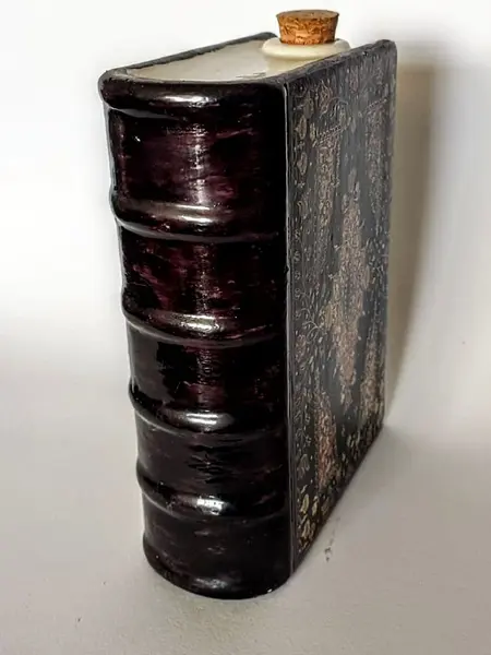 Foto de um(a) Livro Decorativo em Porcelana Anos 60, da categoria de Objetos decorativos. Livro fake em porcelana policromada para bebidas com tampa de rolha, capa e contra capa trabalhada, década de 1960. A: 17 cm... Mostrado de uma perspectiva diferente. Vendido no marketplace Trésors.