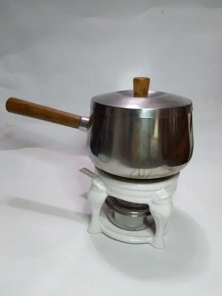 Foto de um(a) Panela de Fondue com Rechaud em Porcelana, da categoria de Panelas. Panela de fondue em inox e suporte em porcelana. A: 24cm / Diâmetro: 16cm. Mostrado de uma perspectiva diferente. Vendido no marketplace Trésors.