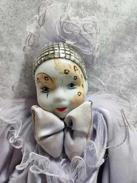 Foto de um(a) Pierrot em Porcelana, Década de 1970, da categoria de Bonecas. Pierrô em porcelana com vestimentas em cetim na cor lilás, corpo em tecido com enchimento e membros móveis. Cabeça com tiara... Mostrado de uma perspectiva diferente. Vendido no marketplace Trésors.