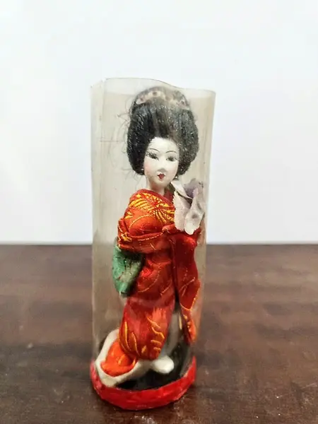 Foto de um(a) Pequena Gueixa Japonesa, Década de 1960, da categoria de Modelos e estatuetas. Pequena gueixa com seu quimono original dos anos 1960. Ainda com a embalagem. A: 12 cm / Diâmetro: 4,6 cm / Peso: 38 g. Mostrado de uma perspectiva diferente. Vendido no marketplace Trésors.