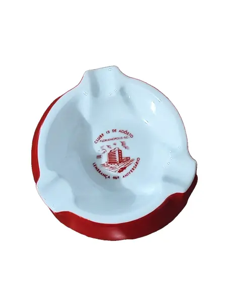 Foto de um(a) Cinzeiro Porcelana Steatita, Década de 1960, da categoria de Cinzeiros e coletores. Cinzeiro de mesa em porcelana branca com moldura em vermelho e o logo do clube 12 de agosto, fundado em 12 de agosto de 1872... Vendido no marketplace Trésors.