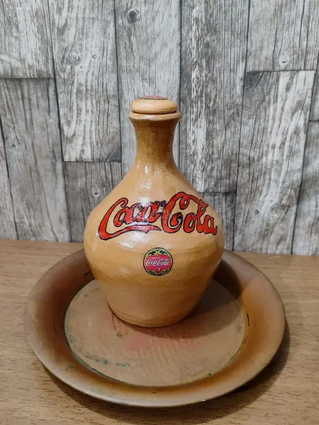 Foto de um(a) Moringa Coca-Cola, da categoria de Garrafas, potes e jarros. Coca cola raíz é outra coisa! Direto do sul de minas gerais, uma velha moringa de barro personalizada. Peça única pelo... Mostrado de uma perspectiva diferente. Vendido no marketplace Trésors.