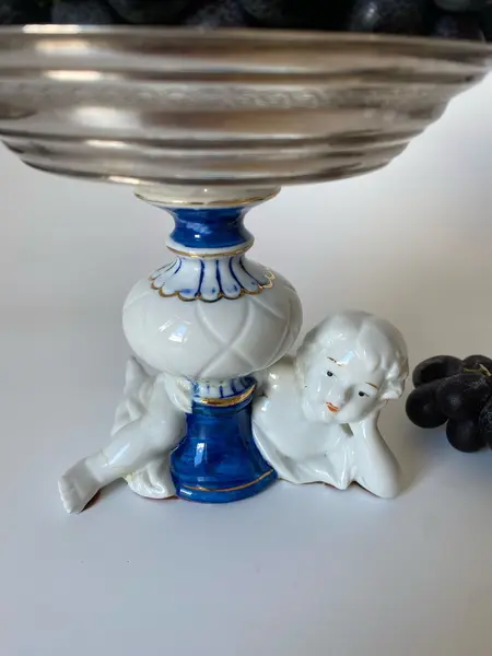 Foto de um(a) Fruteira de porcelana, da categoria de Travessas e tigelas. Pequena fruteira em porcelana e metal. Apresenta um restauro no pé. Mede: 13 x 14cm. Mostrado de uma perspectiva diferente. Vendido no marketplace Trésors.