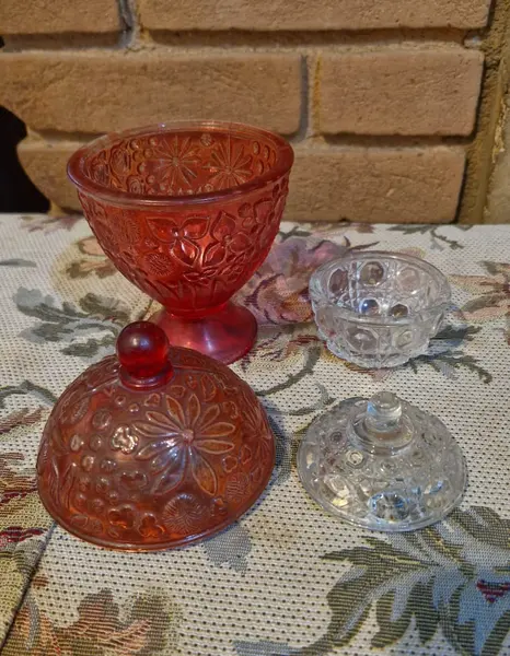 Foto de um(a) 2 belas bomboniéres, sendo uma da Avon anos 60, da categoria de Garrafas, potes e jarros. Duas belas bombonières de vidro decorativas (potes com tampa), sendo a vermelha um modelo clássico de colecionador da marca... Mostrado de uma perspectiva diferente. Vendido no marketplace Trésors.