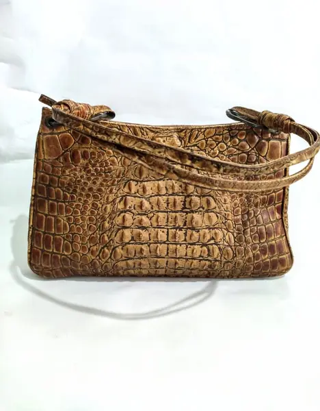 Foto de um(a) Bolsa Caramel Croco Anos 70, da categoria de Bolsas. Bolsa e alças em couro de crocodilo na cor caramelo, década de 1970. A: 22 cm L: 35 cm P: 8 cm Peso: 550 g. Mostrado de uma perspectiva diferente. Vendido no marketplace Trésors.