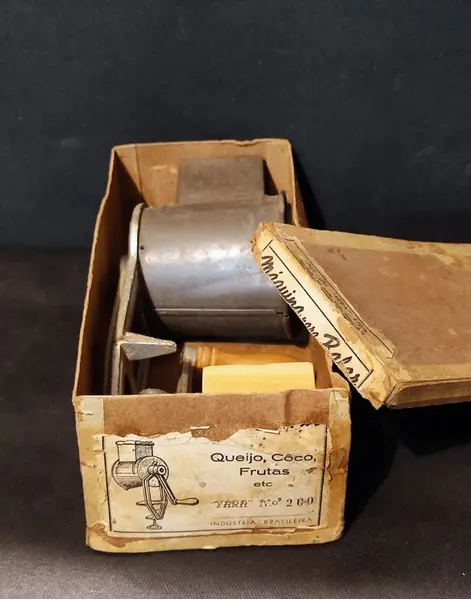 Foto de um(a) Ralador de Queijo e Frutas, Marca Yara N.200, Década de 1940, da categoria de Acessórios de cozinha. Máquina de ralar queijo, coco e frutas. Em ferro, folha de flanders e socador e manivela em madeira, com embalagem original... Mostrado de uma perspectiva diferente. Vendido no marketplace Trésors.