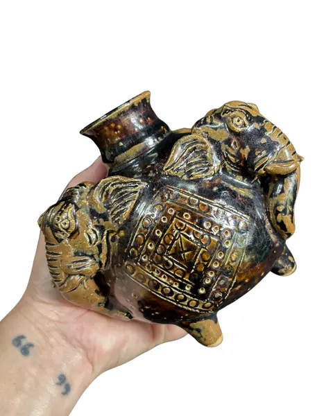 Foto de um(a) Vaso Elefantes Cerâmica, da categoria de Vasos. Vaso em cerâmica, representando 3 cabeças de elefantes, esmaltação na cor café/chocolate, aspecto rústico artesanal... Mostrado de uma perspectiva diferente. Vendido no marketplace Trésors.
