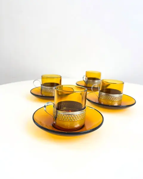 Foto de um(a) Conjunto com 04 xícaras Duralex para café, com suporte em metal, da categoria de Conjuntos de café e chá. Jogo com 4 xícaras e pires Duralex para café. Pontos de oxidação no metal. Mostrado de uma perspectiva diferente. Vendido no marketplace Trésors.