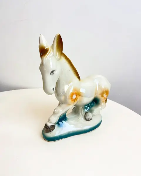 Foto de um(a) Escultura bibelô Burrinho em porcelana pintada, da categoria de Escultura. Burrinho em porcelana pintada. Está com alguns desgastes na pintura como mostrado nas fotos. Mede 18x17cm. Mostrado de uma perspectiva diferente. Vendido no marketplace Trésors.