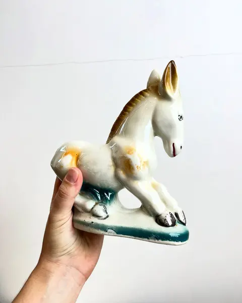 Foto de um(a) Escultura bibelô Burrinho em porcelana pintada, da categoria de Escultura. Burrinho em porcelana pintada. Está com alguns desgastes na pintura como mostrado nas fotos. Mede 18x17cm. Mostrado de uma perspectiva diferente. Vendido no marketplace Trésors.