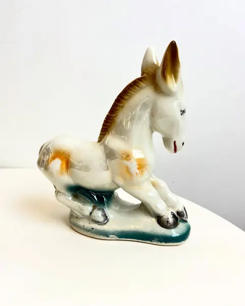 Foto de um(a) Escultura bibelô Burrinho em porcelana pintada, da categoria de Escultura. Burrinho em porcelana pintada. Está com alguns desgastes na pintura como mostrado nas fotos. Mede 18x17cm. Mostrado de uma perspectiva diferente. Vendido no marketplace Trésors.