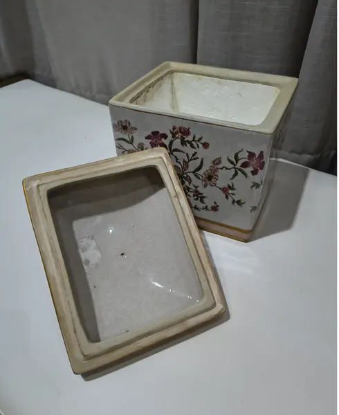 Foto de um(a) Antigo Pote Decorativo em Faiança com Tampa Floral, da categoria de Garrafas, potes e jarros. Produzido em porcelana/faiança de excelente espessura, a peça apresenta formato retangular e uma belíssima pintura botânica... Mostrado de uma perspectiva diferente. Vendido no marketplace Trésors.
