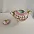 Foto de um(a) Vaso em Porcelana Branco com Pinturas de Rosas, da categoria de Vasos. Vaso em porcelana de coloração branca, com detalhes em rosa e dourado. Pintura representando flores. Mostrado de uma perspectiva diferente. Vendido no marketplace Trésors.