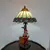 Foto de um(a) Abajur estilo Tiffany com escultura de palhaço, da categoria de Abajures. Bellisimo abajur estilo Tiffany com escultura de palhaço lendo livro. Medidas: altura 48 cm x diâmetro cúpula 28 cm x base... Mostrado de uma perspectiva diferente. Vendido no marketplace Trésors.