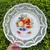 Foto de um(a) Antigo Grande Prato Medalhão Porcelana Alemã Fenestrado, da categoria de Pratos Decorativos. Schumann, Bavaria. Germany. Antigo e grande prato medalhão decorativo com decoração de frutas, dita natureza morta, borda... Mostrado de uma perspectiva diferente. Vendido no marketplace Trésors.