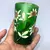 Foto de um(a) Antigo Copo Em Vidro Veneziano Verde Art Nouveau Pintado Mao, da categoria de Copos e taças. Início do século XX, ricamente pintado à mão.Medidas 10x6,5cm. Mostrado de uma perspectiva diferente. Vendido no marketplace Trésors.
