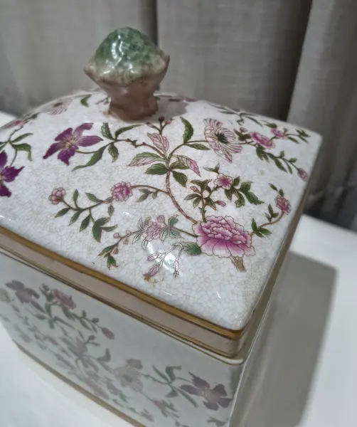 Foto de um(a) Antigo Pote Decorativo em Faiança com Tampa Floral, da categoria de Garrafas, potes e jarros. Produzido em porcelana/faiança de excelente espessura, a peça apresenta formato retangular e uma belíssima pintura botânica... Mostrado de uma perspectiva diferente. Vendido no marketplace Trésors.