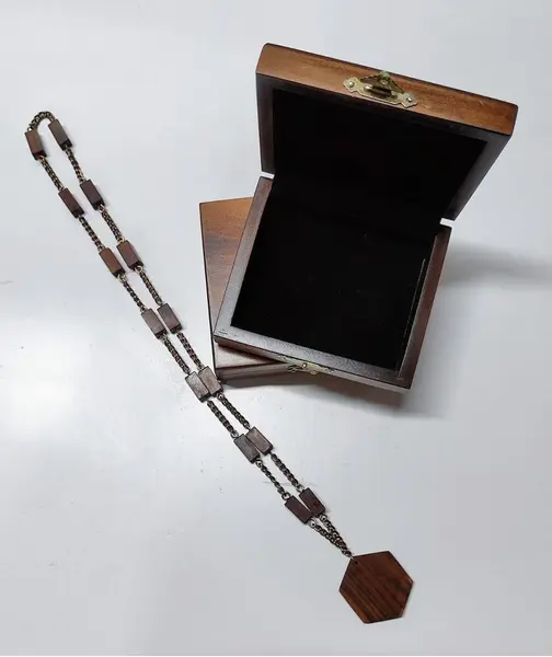 Foto de um(a) Colar em Jacarandá com Medalhão Signo de Sagitário, Década de 1970, da categoria de Outros colecionáveis. Colar de madeira de jacarandá dos anos 1970: corrente com 14 retângulos com base quadrada, unidos por corrente dourada... Mostrado de uma perspectiva diferente. Vendido no marketplace Trésors.