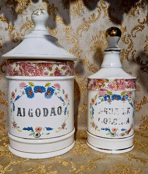 Foto de um(a) Raro e antigo par de potes de farmácia, da categoria de Garrafas, potes e jarros. Conjunto com 2 potes antigos de farmácia, sendo um de algodão e o outro de água de colônia. Ambos em porcelana com... Mostrado de uma perspectiva diferente. Vendido no marketplace Trésors.
