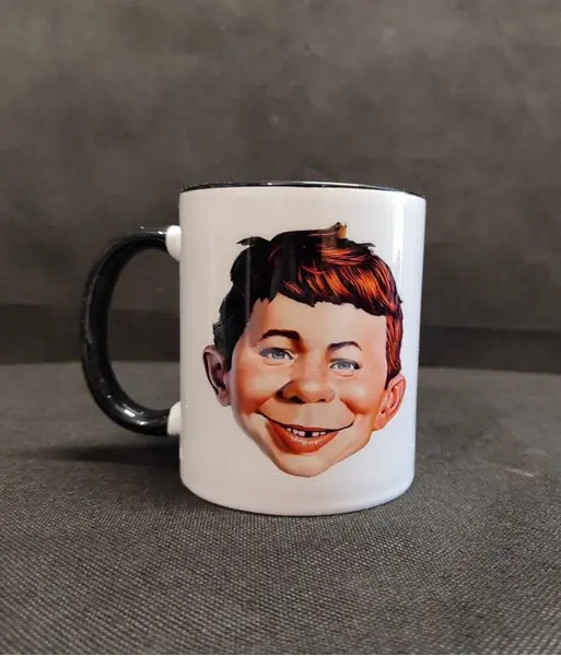 Foto de um(a) Caneca Bom Alfredo, Alfred E. Neuman da Revista Mad, da categoria de Canecas. Caneca alfred e. Neuman da revista mad: um clássico que marcou época. Teve seu início em 1954. Caneca em porcelana com alça... Mostrado de uma perspectiva diferente. Vendido no marketplace Trésors.