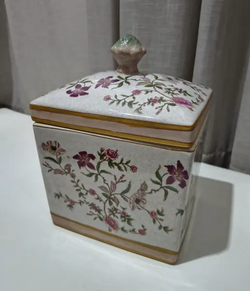 Foto de um(a) Antigo Pote Decorativo em Faiança com Tampa Floral, da categoria de Garrafas, potes e jarros. Produzido em porcelana/faiança de excelente espessura, a peça apresenta formato retangular e uma belíssima pintura botânica... Mostrado de uma perspectiva diferente. Vendido no marketplace Trésors.