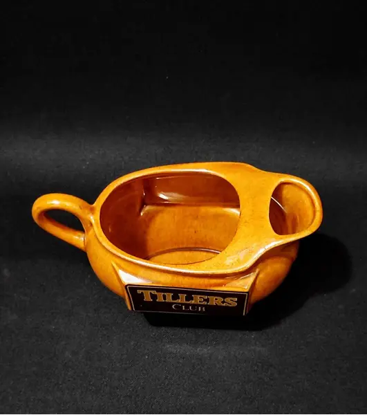Foto de um(a) Molheira Escocesa Tillers Club, Década de 1980, da categoria de Cremeiras. Molheira com logo da tillers club dos anos 1980 em porcelana na cor âmbar.A: 10 cm L: 15,5 cm L com alça: 19,4 cm P: 9 cm... Mostrado de uma perspectiva diferente. Vendido no marketplace Trésors.